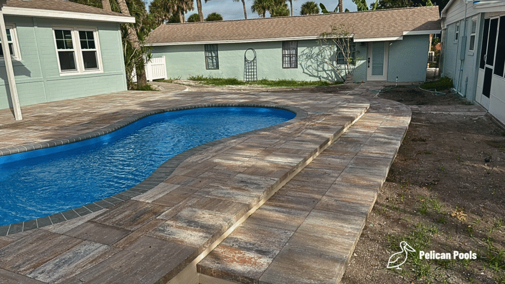 Cocoa Beach fiberglass swimming pool with bench seating and steps, installed by Pelican Pools in Volusia County with a custom paver deck.