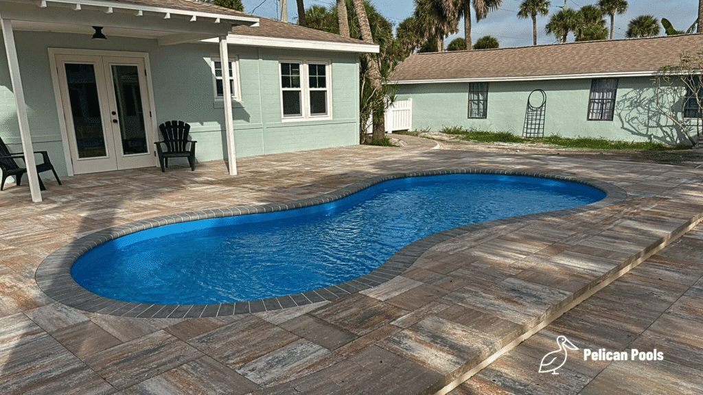 Cocoa Beach freeform pool with curved sport design, installed by Pelican Pools in Volusia County with a custom paver deck.