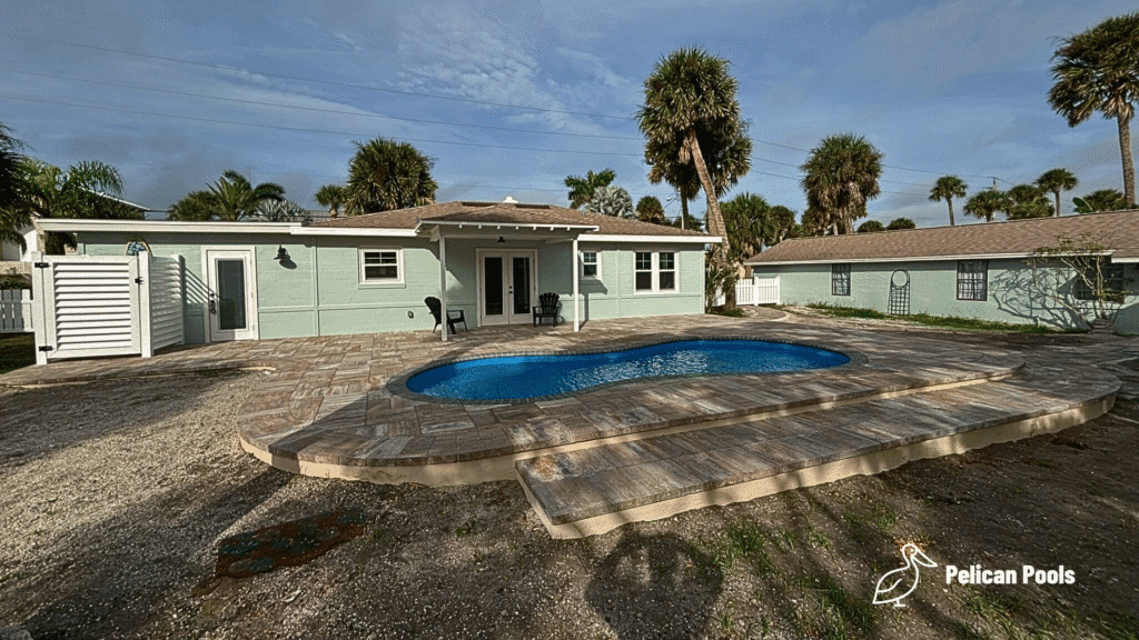 Cocoa Beach fiberglass pool with shallow end bench and relaxation area, installed by Pelican Pools in Volusia County with a custom paver deck.