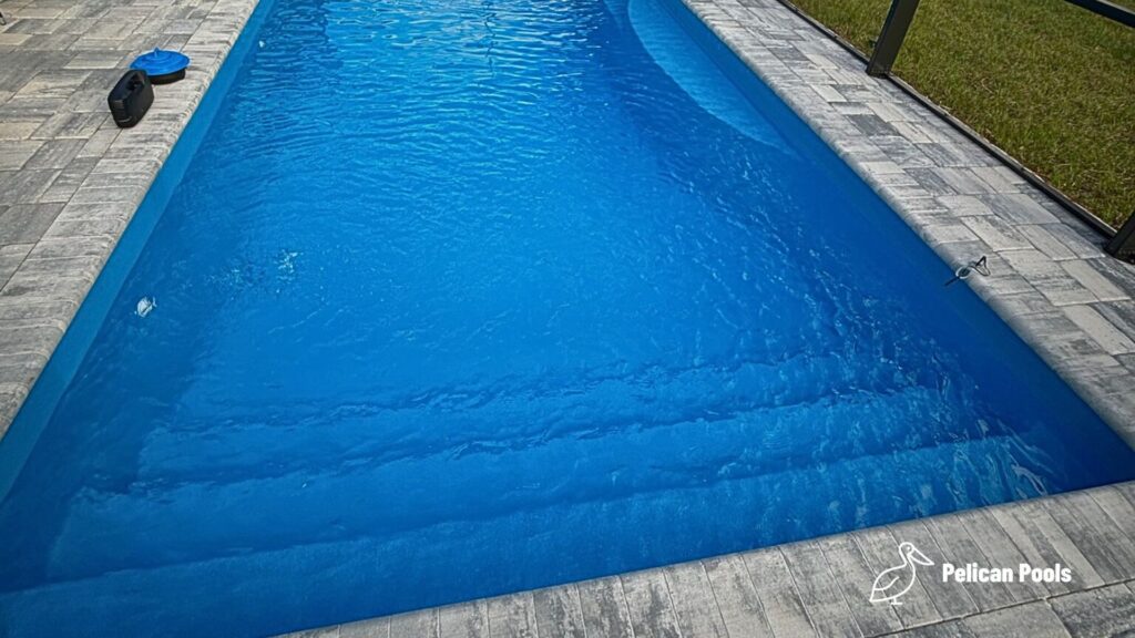 Wylela fiberglass pool installed by Pelican Pools in Palm Coast, Florida with paver deck.