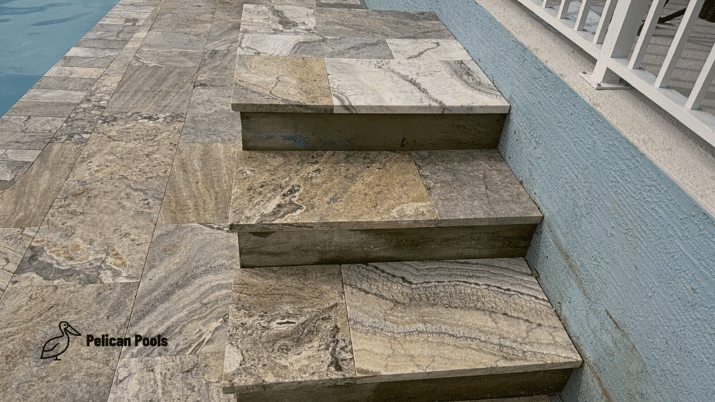 Travertine steps connecting pool deck to lanai with precise stone alignment.