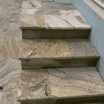 Travertine steps connecting pool deck to lanai with precise stone alignment.