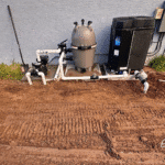 Complete pool equipment setup including pump, filter, and heater next to home.