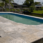 Fiberglass pool with travertine paver deck overlooking canal.