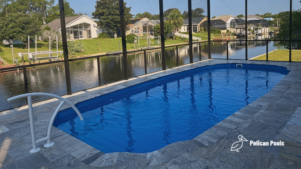 Blue fiberglass pool water inside screened lanai with canal view.