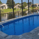 Blue fiberglass pool water inside screened lanai with canal view.