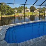 Blue fiberglass pool with screened enclosure and canal view in Palm Coast.