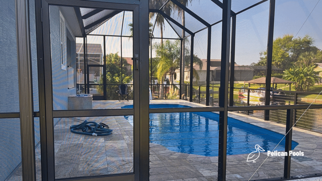 Screened enclosure surrounding a fiberglass pool viewed from the lanai door.