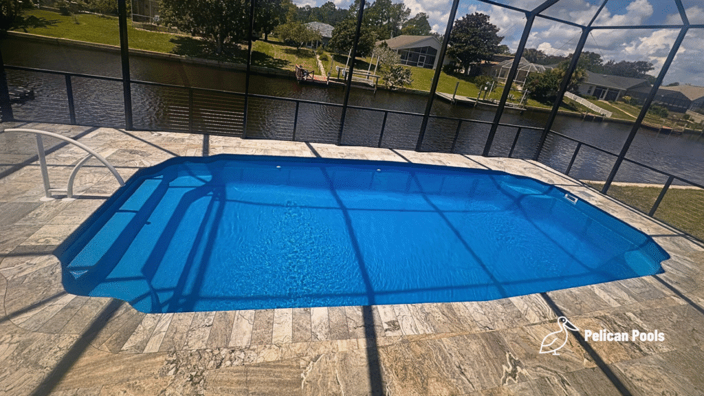 Elevated view of fiberglass pool showing deck pattern and canal reflection.