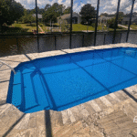 Hawaiian fiberglass pool viewed from side of screened enclosure.