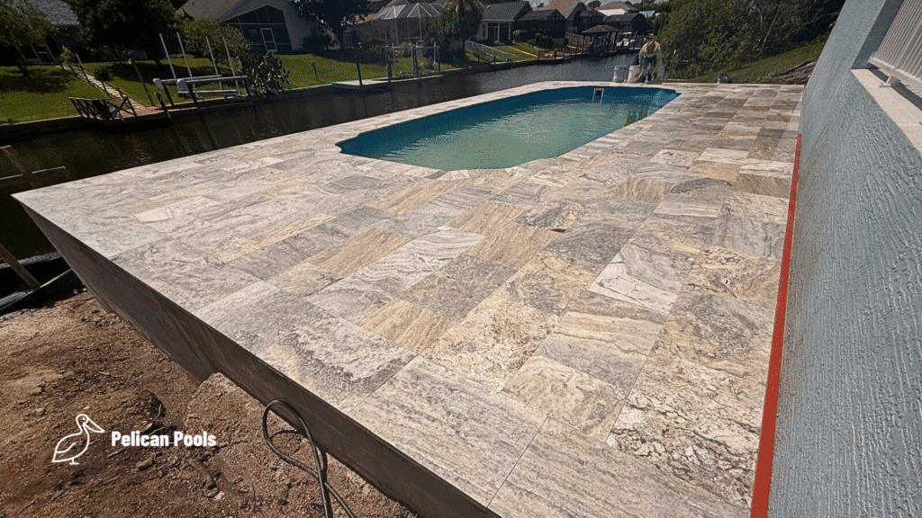 Finished fiberglass pool with stone paver deck overlooking canal.