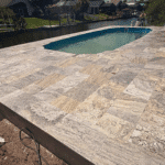 Finished fiberglass pool with stone paver deck overlooking canal.