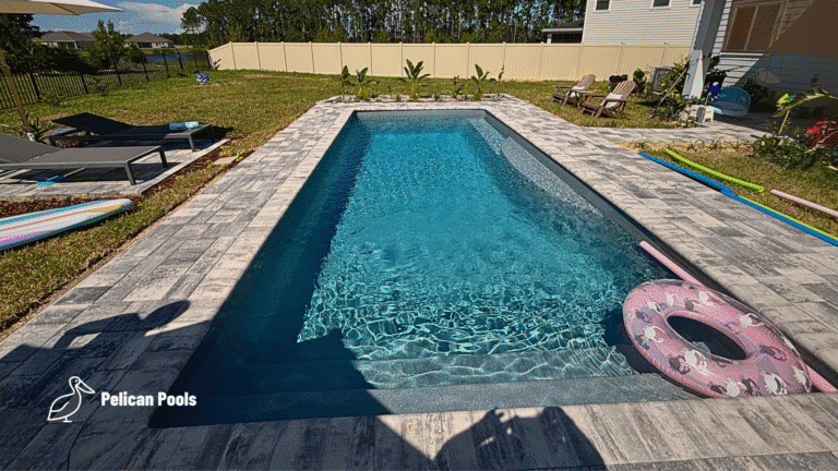Pool with paver deck, surfboard-style float, and poolside garden beds.