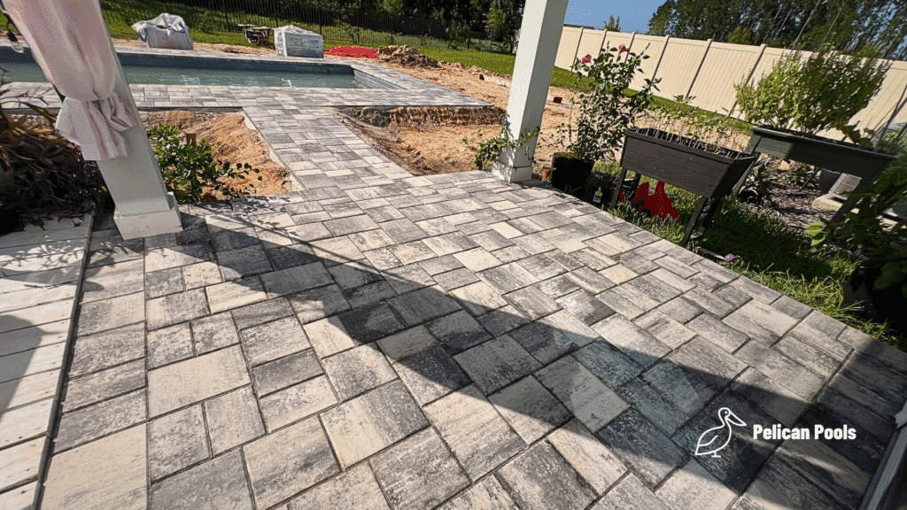 Paver walkway connecting pool deck to covered patio.