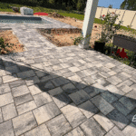 Paver walkway connecting pool deck to covered patio.