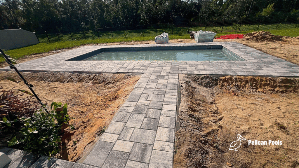 Backyard pool with fresh landscaping and finished deck.