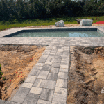 Backyard pool with fresh landscaping and finished deck.