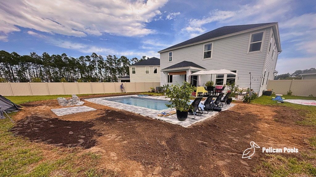 Completed fiberglass pool installation with patio furniture and garden plants.
