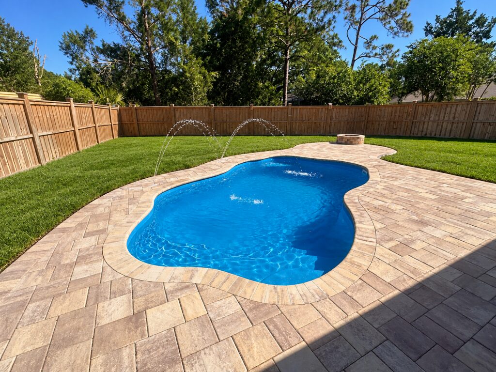 Ariella pool installation from the entry-step end with stone pavers and jets; yard digitally cleaned and grass enhanced.