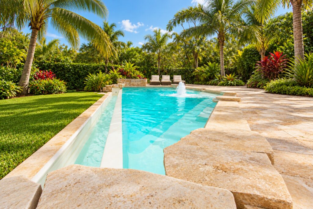 San Juan iPool showing a long submerged bench, underwater steps and a bubbler beside a tropical travertine terrace.