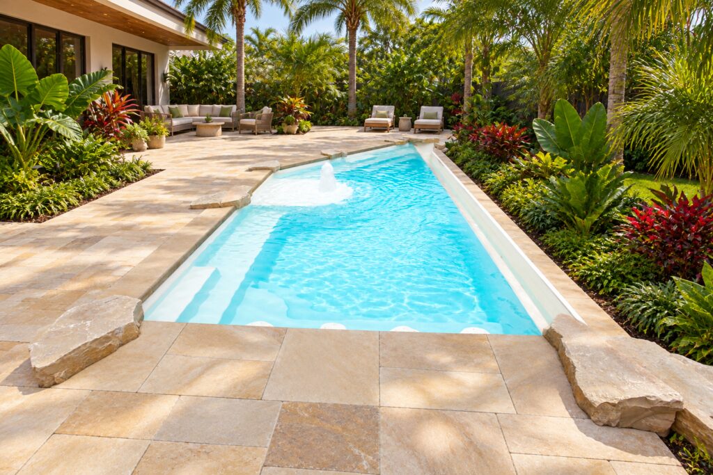 San Juan iPool with integrated underwater steps, a side bench and bubbler in a tropical courtyard with stone paving.