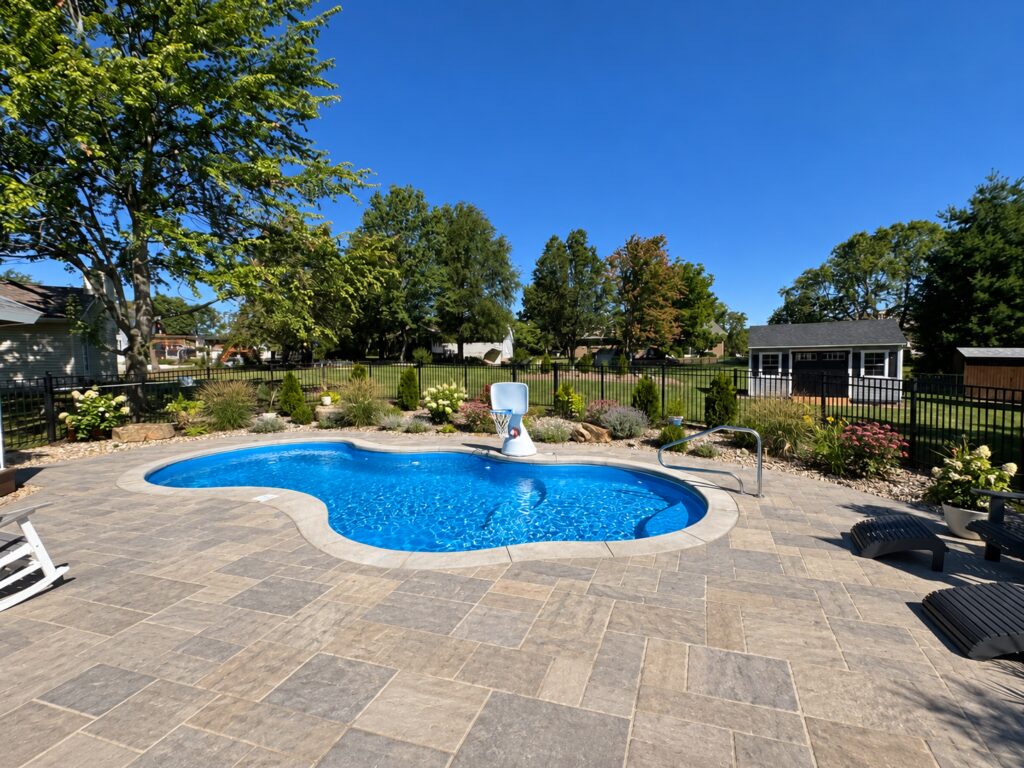 Edited design inspiration showing a Costa Azul pool with gray natural stone paving, flowering garden borders, basketball hoop and entry rail.