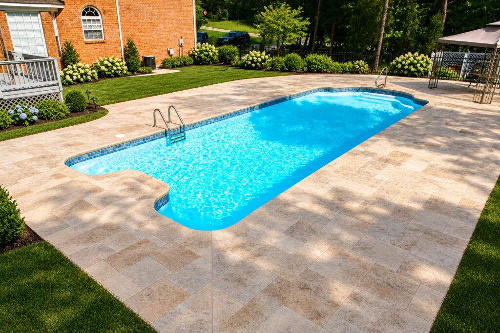 Dallas pool beside a brick home with travertine paving and green lawn. Digitally edited design inspiration.