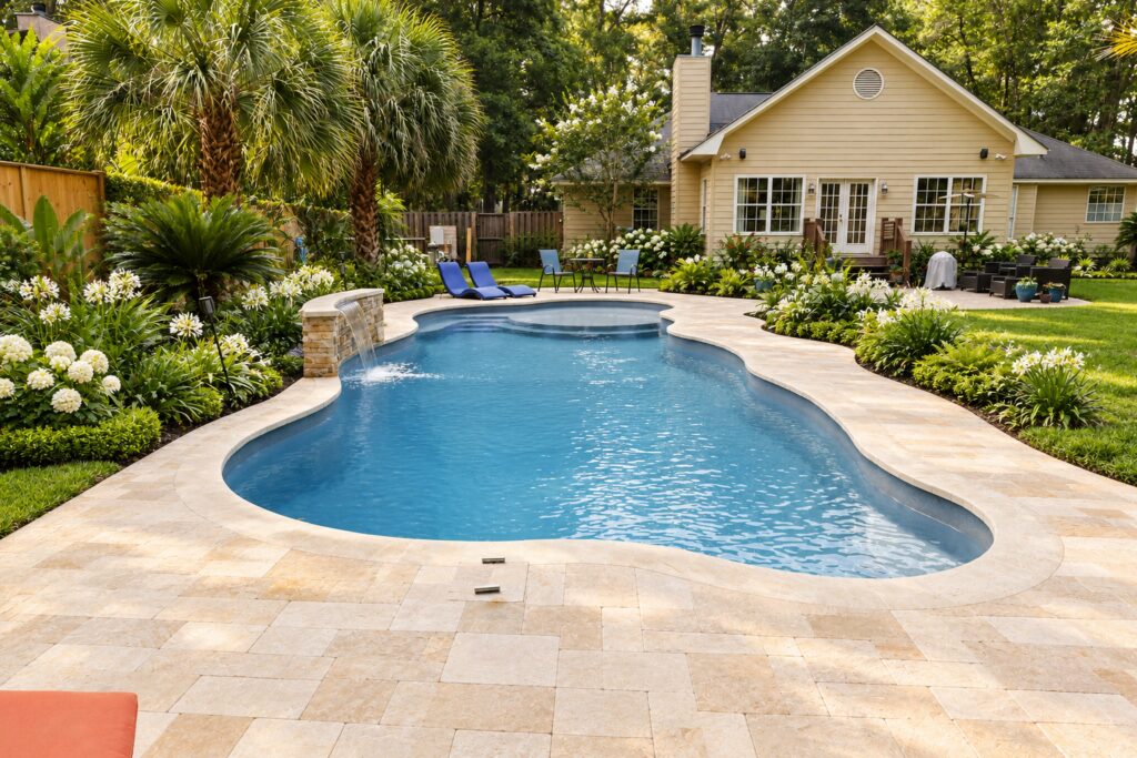San Juan Daytona Beach Pool – Tropical Limestone Design Inspiration Daytona Beach pool with limestone patio and tropical garden beside a yellow house. Digitally edited design inspiration.